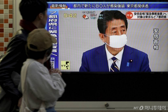 아베 신조(安倍晋三) 일본 총리가 지난 7일(화) 도쿄에서 국가비상사태를 선포하는 가운데 한 보행자가 TV 뉴스를 보기 위해 멈춰서있다. / 사진=ap뉴시스