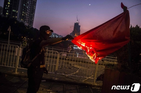 마스크를 착용한 홍콩의 한 시위자가 중국 오성홍기에 불을 붙이고 있다. © AFP=뉴스1