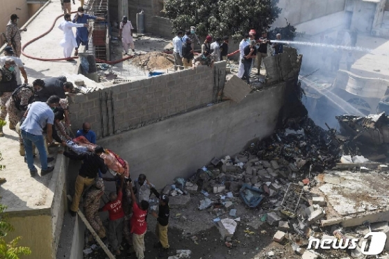 22일 파키스탄 카라치의 한 주거지역에 파키스탄국제항공 여객기가 추락한 현장에서 구조 작업이 이뤄지고 있다. © AFP=뉴스1