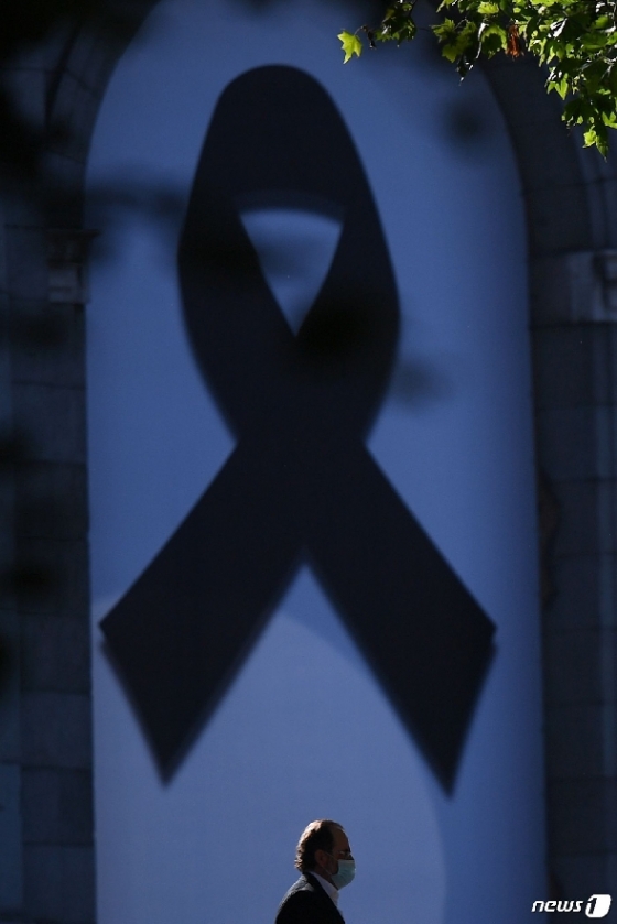 코로나19 희생자를 기리는 검은 리본앞을 한 행인이 지나고 있다. © AFP=뉴스1