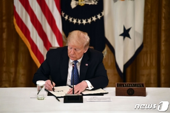도널드 트럼프 미국 대통령이 19일(현지시간) 워싱턴 백악관에서 각료회의를 열고 경제회복을 위한 행정명령에 서명을 하고 있다. © AFP=뉴스1