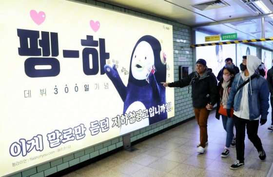  서울 강남구 삼성역에 설치된 펭수 데뷔 300일 기념 지하철 광고를 관광객들이 지나가며 바라보고 있다./ 사진=뉴시스