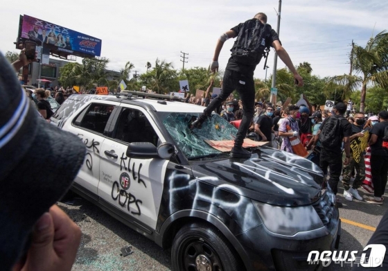 (로스앤젤레스 AFP=뉴스1) 우동명 기자 = 30일(현지시간) 캘리포니아주 로스앤젤레스에서 비무장 흑인 남성 조지 플로이드의 백인 경찰 가혹 행위로 숨진 사건에 항의하는 시위대가 경찰 차량을 파손하고 있다.  ⓒ AFP=뉴스1