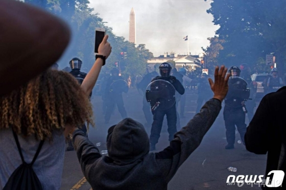 (AFP=뉴스1) 이동원 기자 = 도널드 트럼프 미국 대통령은 1일(현지시간) 흑인 남성 조지 플로이드의 사망에 항의하는 시위와 관련해 폭동 진압을 위해 군대를 동원할 수 있다고 말했다.  1일(현지시간) 워싱턴 D.C.에서 폭동 진압 장비를 착용한 경찰들이 흑인 조지 플로이드의 죽음에 대한 항의시위대를 향해 최루탄을 발사하며 백악관 밖에서 밀어내고 있다. 미국의 주요 도시들은 폭동을 진압하기 위해 통행금지를 당했다.  ⓒ AFP=뉴스1