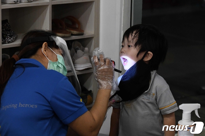 싱가포르에서 한 의료진이 아이에게 코로나19 검사를 실시하고 있다. © AFP=뉴스1