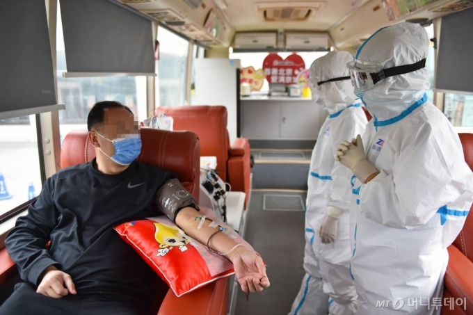 [베이징=신화/뉴시스]27일 중국 베이징의 한 헌혈 버스에서 신종 코로나바이러스 감염증(코로나19) 완치 남성이 혈장 헌혈을 하고 있다. 현지 관계자는 이날 2명의 코로나19 완치자가 헌혈 버스에서 혈장 헌혈을 했다고 밝혔다. 2020.02.27.