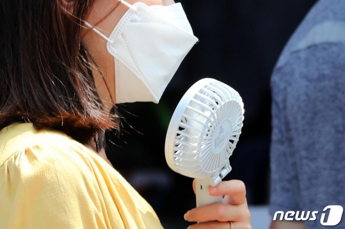더운 여름 날씨가 이어진 6일 오후 경기도 수원시 팔달구 영동시장에서 한 시민이 마스크를 쓴 채 손 선풍기로 더위를 식히고 있다. /사진=뉴스1