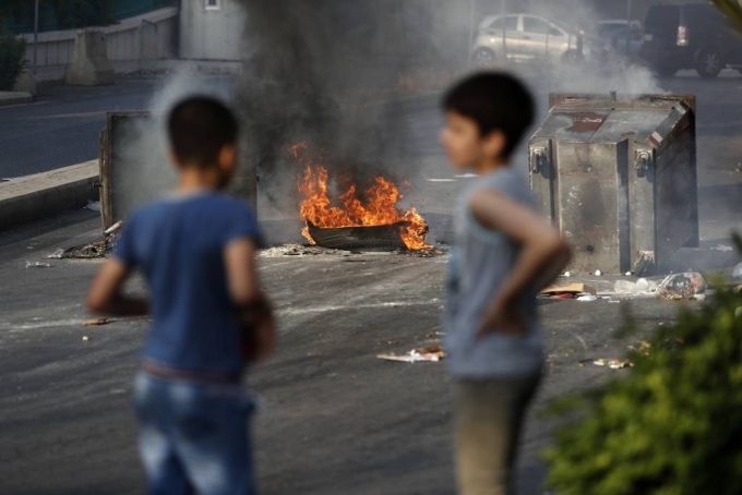 [베이루트=AP/뉴시스]6월 30일(현지시간) 레바논 베이루트에서 반정부 시위대가 도로를 봉쇄하기 위해 불을 지른 타이어와 쓰레기통 앞에 두 소년이 서 있다. 2020.07.01.