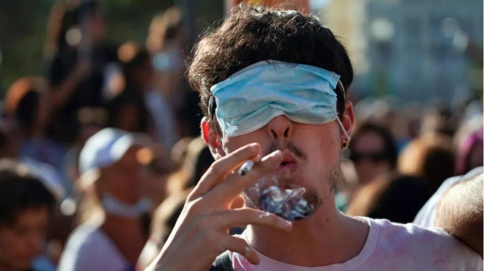 16일(현지시간) 스페인 마드리드에서 마스크 사용 반대 시위에 참여한 한 남성이 마스크로 눈을 가리고 담배를 피우고 있다./로이터=뉴스1