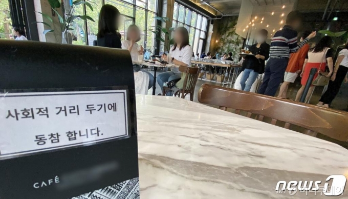 (서울=뉴스1) 이동해 기자 = 수도권의 사회적 거리두기 단계가 2.5단계에서 2단계로 2주간 조정된 13일 서울 시내 카페거리의 한 카페에 시민들로 북적이는 가운데 거리두기 동참 의미로 테이블이 비어져 있다. 2020.9.13/뉴스1