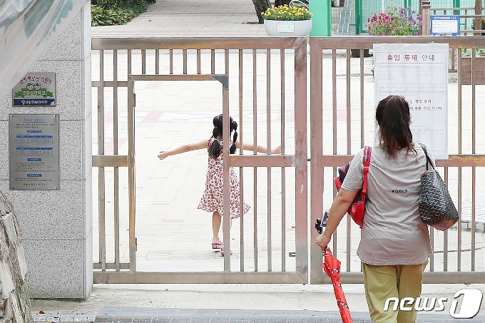 서울의 한 초등학교에서 지난 16일 한 어머니가 자녀를 오후 돌봄교실에 바래다주고 있다. /뉴스1 © News1 민경석 기자