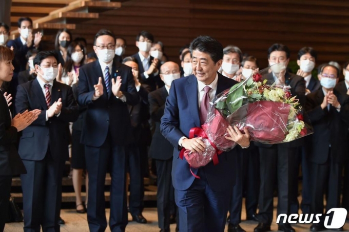 퇴임하는 아베 신조 일본 총리가 16일(현지시간) 도쿄 총리관저에서 마지막 각료회의를 마친 뒤 직원들로부터 받은 꽃다발을 들고 고개를 숙이며 작별인사를 하고 있다.  /사진= AFP=뉴스1