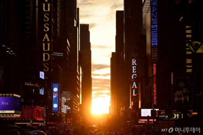 미국 뉴욕 타임스퀘어 인근 42번가에 '맨해튼헨지' 현상을 보기 위해 몰려든 인파들이 사진을 찍고 있다. '맨해튼헨지'는 매년 5월말과 7월초 태양이 질 때 거리와 나란히 놓여 빛이 비치는 현상으로 뉴욕시의 대표적인 경치이다ⓒ 로이터=뉴스1 / 사진제공=로이터