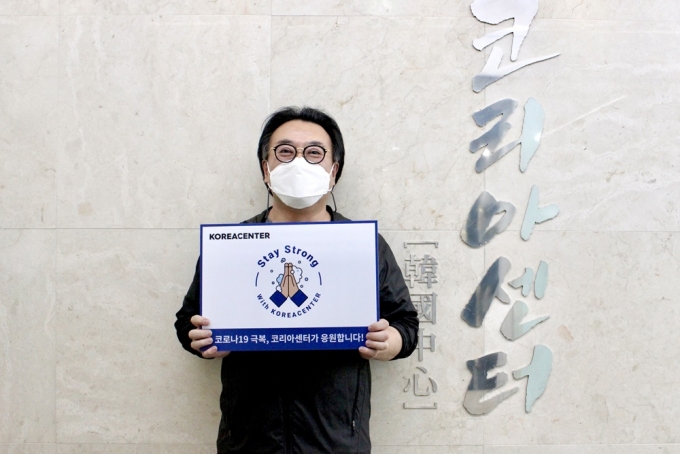 김기록 대표가 "코로나19 극복 코리아센터가 응원한다"라는 문구가 적힌 손 팻말을 들고 캠페인에 참여했다.