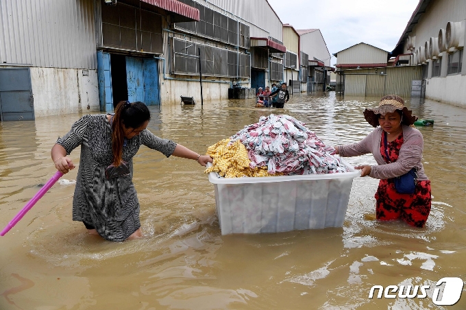 [사진] 물바다 거리서 의류 상자와 옮기는 캄보디아 근로자