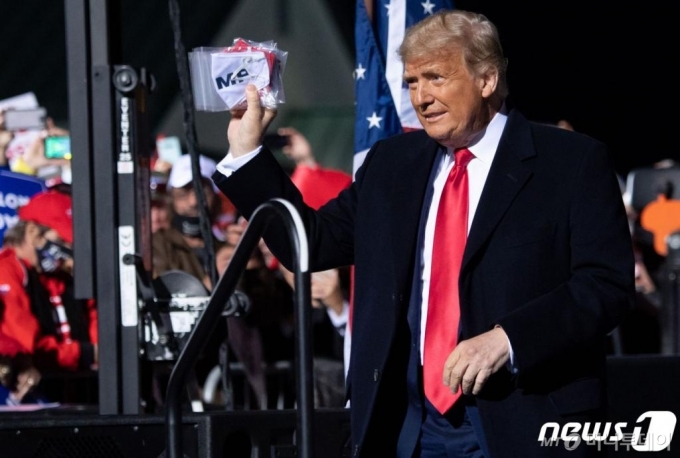 (존스타운 AFP=뉴스1) 우동명 기자 = 도널드 트럼프 미국 대통령이 13일(현지시간) 펜실베이니아주 존스타운 공항에서 열린 선거집회에 도착하면서 마스크를 들어보이고 있다.  ⓒ AFP=뉴스1