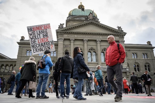 18일 한 시민이 스위스 국회 앞에서 코로나19 제한 조치에 항의하는 팻말을 들고 있다. 스위스 연방정부는 모든 실내 공공장소에서 마스크 착용을 의무화하고, 공공장소에서 15인 이상 모임을 금지했다./사진제공=AFP