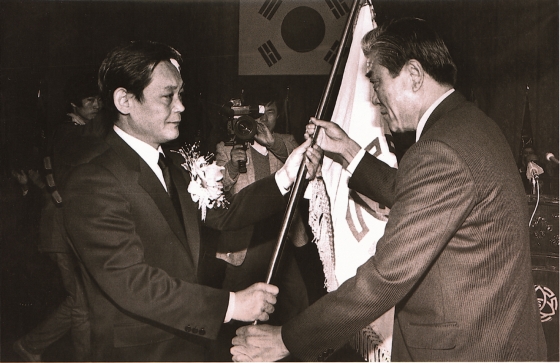 1987년 12월 이건희 삼성 회장이 취임식에서 당시 입사일이 가장 빨랐던 최관식 삼성중공업 사장으로부터 삼성 사기를 받고 있는 모습.