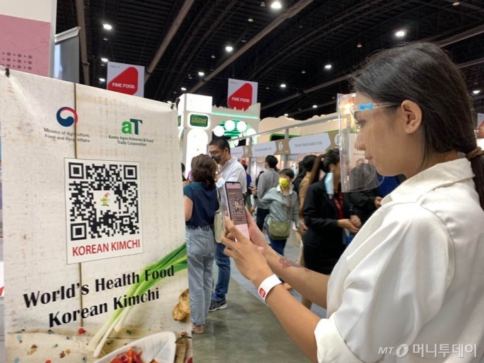 한 태국 대형유통매장을 찾은 소비자가 한국 김치에 대한 이해를 돕기위해 제작된 'QR코드'를 통해 자세한 정보를 확인하고 있다. /사진=aT
