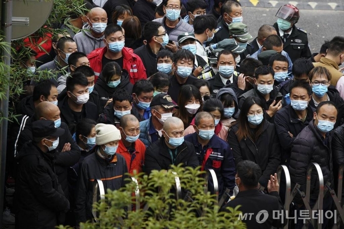 [상하이=AP/뉴시스]23일 중국 상하이 푸둥 국제공항에서 마스크를 쓴 노동자들이 코로나19 검사를 받기 위해 모여드는 가운데 주차장 입구에서 한 관계자가 무언가를 설명하고 있다. 중국 당국은 지난 사흘간 푸둥 국제공항을 중심으로 연속 확진자가 보고되면서 시내 주거지역 3곳을 봉쇄하고 수백만 명의 사람을 검사하는 등 비상이 걸렸다. 2020.11.23.
