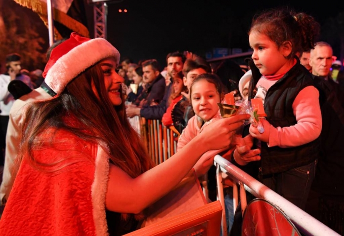 [다마스쿠스(시리아)=신화/뉴시스]산타클로스 복장을 한 여성이 22일(현지시간) 시리아 수도 다마스쿠스 서쪽 마제 고속도로에 세워진 크리스마스트리 근처에서 어린이들에게 사탕을 나눠주고 있다. 이날 크리스마스트리 주변에서 음악회가 열리고 산타클로스로 분장한 어른들이 어린이들에게 사탕을 나눠주는 행사가 열렸다. 2019.12.23.