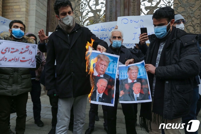 자국 과학자를 암살한 테러를 규탄하며 28일 시위를 벌이는 이란인들이 도널드 트럼프 미국 대통령과 조 바이든 대통령 당선인의 사진을 불태우고 있다. © AFP=뉴스1