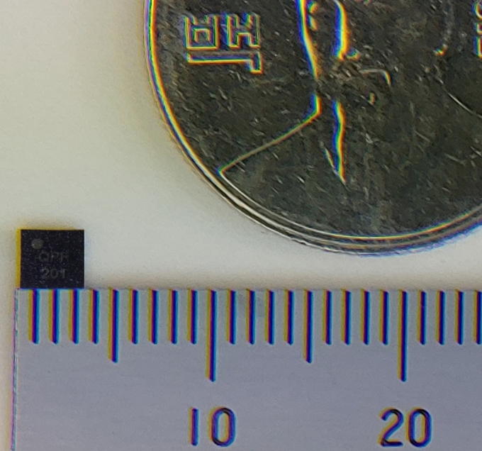 이번에 개발된 IoT 단말용 초소형 양자보안칩과 100원짜리 동전의 크기를 비교하는 모습. /사진=LG유플러스