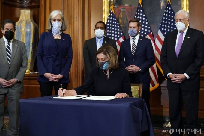 [워싱턴=AP/뉴시스]낸시 펠로시 미 하원의장이 13일(현지시간) 의회에서 도널드 트럼프 대통령의  탄핵소추안에 서명하고 있다. 펠로시 의장은 "오늘 하원은 그 누구도 법 위에 있지 않다는 것을 증명했다"라고 하원의 탄핵소추안 가결을 평가했다. 2021.01.14.