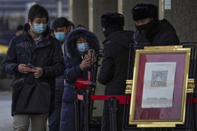 [베이징=AP/뉴시스]12일 중국 베이징의 한 공원에서 코로나19 예방을 위해 마스크를 쓴 사람들이 한 건물에 들어가기 전 QR 코드를 인식시키고 있다. 2021.01.12.