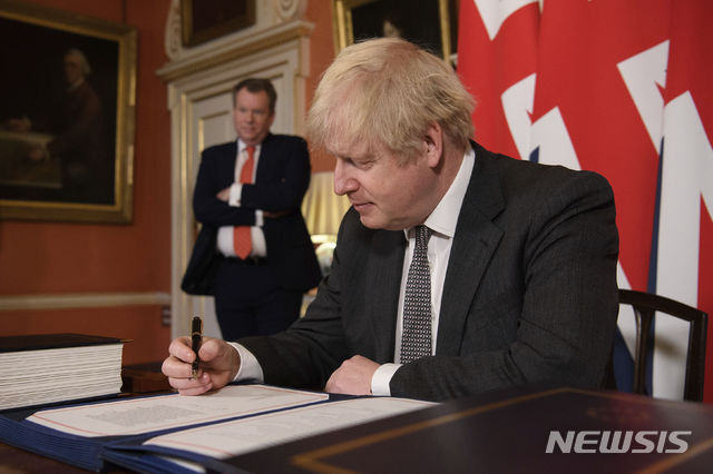 [런던=AP/뉴시스]보리스 존슨 영국 총리가 30일(현지시간) 런던 총리 관저에서 데이비드 프로스트(왼쪽) 영국 통상교섭본부장이 지켜보는 가운데 브렉시트(영국의 유럽연합 탈퇴) 관련 미래관계 협정 합의안에 서명하고 있다. 2020.12.31.