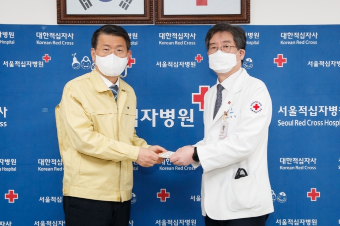 은성수 금융위원장(왼쪽)이 10일 문영수 서울적십자병원장(오른쪽)에게 위로금을 전달하고 있다./사진제공=금융위