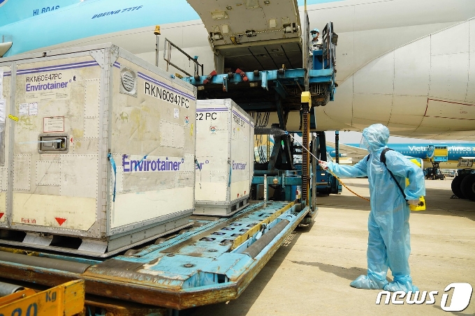 24일 호치민 시 탄손넛 공항에 도착한 아스트라제네카 백신 상자 표면을 한 보건 공무언이 소독하고 있다.© AFP=뉴스1