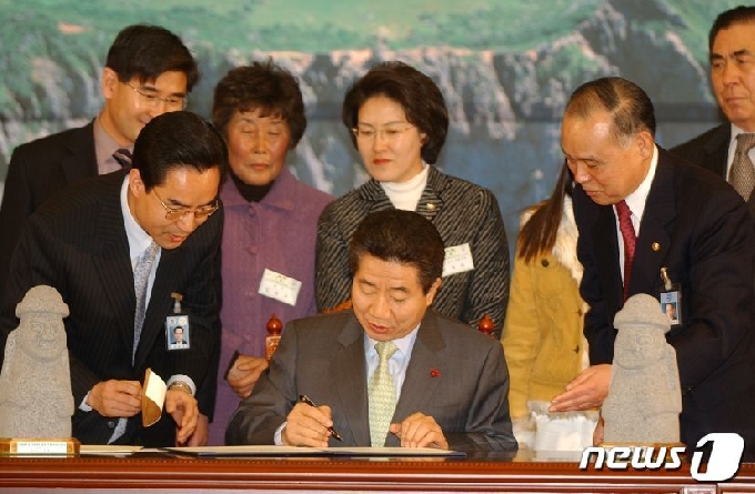 노무현 대통령이 2005년 1월27일 청와대에서 제주 평화의섬 지정 선언문에서 서명하고 있다. © 뉴스1 DB