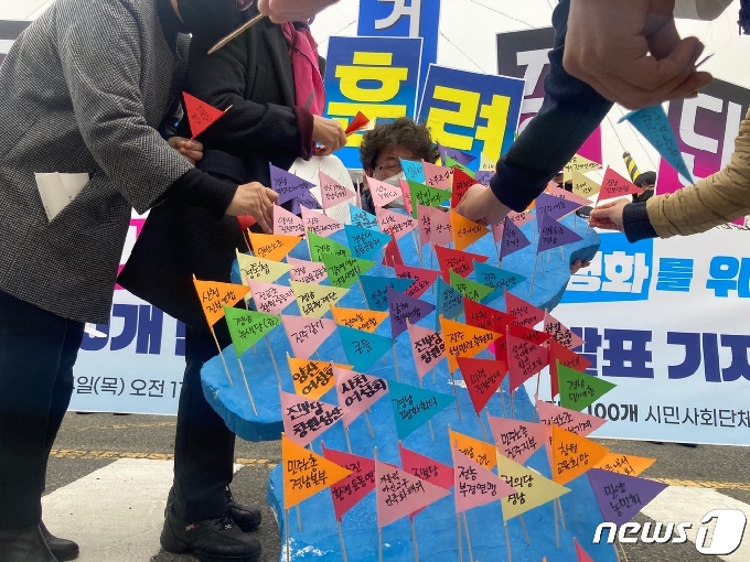 경남 도내 100개 단체는 4일 열린 기자회견을 위해 퍼포먼스를 준비했다. 100개 단체의 이름이 쓰인 깃발을 한반도 모형 위에 꽂으면서 평화를 기원하고 있다. © 뉴스1 김다솜 기자