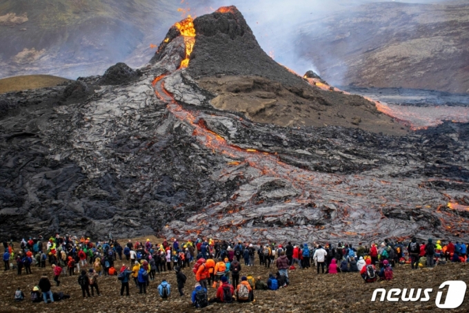 지난 21일(현지시간) 아이슬란드의 레이캬네스 반도의 그린다비크에 있는 파그라달스피아들 화산의 용암 분출을 관광객들이 구경을 하고 있다.  /사진=AFP, 뉴스1