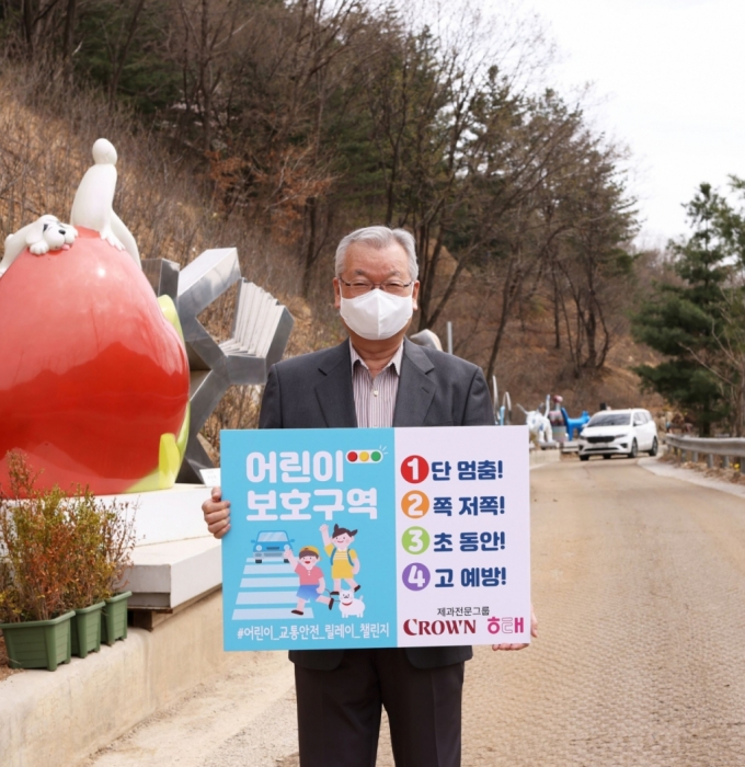 윤영달 크라운해태제과 회장이 어린이 교통안전 표어가 적힌 팻말을 들고 있다./사진= 크라운해태