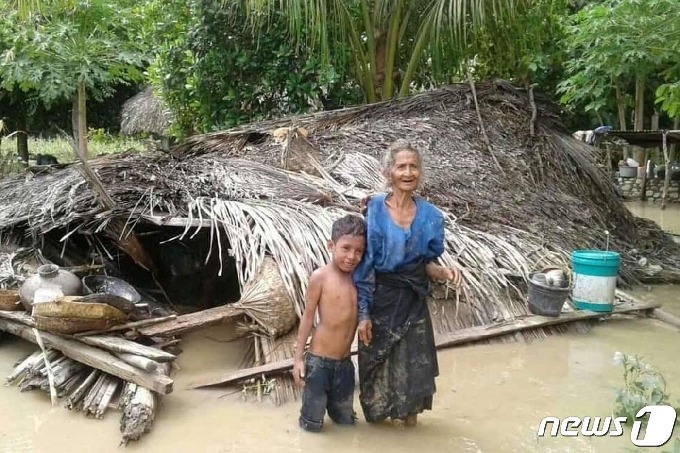 인도네시아 동부와 인근 동티모르를 강타한 홍수와 산사태 구조 작업이 진행 중인 가운데, 2021년 4월 4일 동플로레스 하이티무크 마을의 파손된 집 앞에서 한 노인과 손자가 홍수 속에 서 있다. © AFP=뉴스1