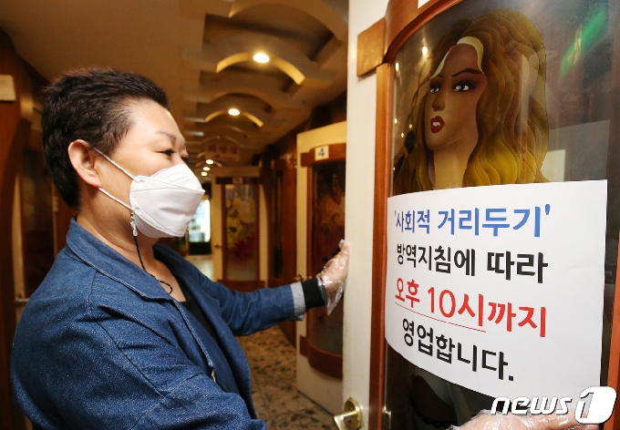 5일 오후 대전 유성구 한 노래방에서 업주가 10시까지 영업한다는 안내문을 붙이고 있다. 2021.4.5/뉴스1 © News1 김기태 기자