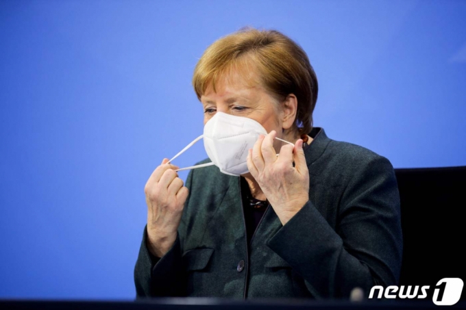(베를린 AFP=뉴스1) 우동명 기자 = 앙겔라 메르켈 독일 총리가 19일 (현지시간) 베를린 총리공관에서 열린 화상 기자회견에 도착해 마스크를 벗고 있다.   (C) AFP=뉴스1  