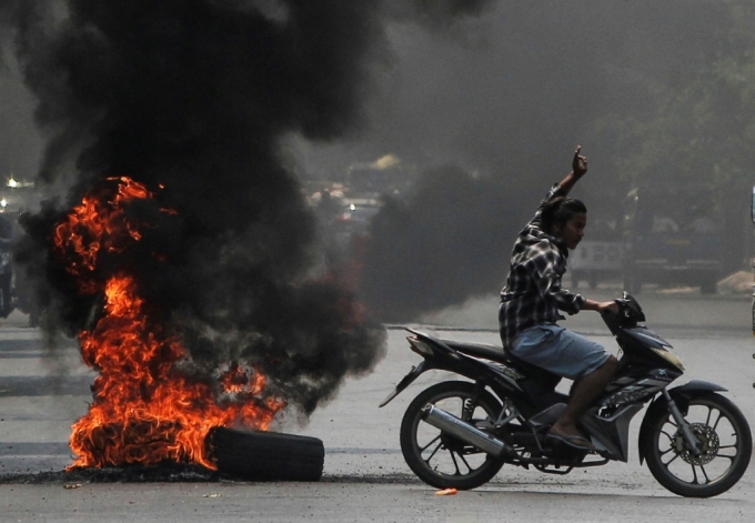 미얀마 만달레이에서 반군부 시위대가 불타는 타이어를 지나며 세 손가락 경례를 해보이고 있다./사진=로이터