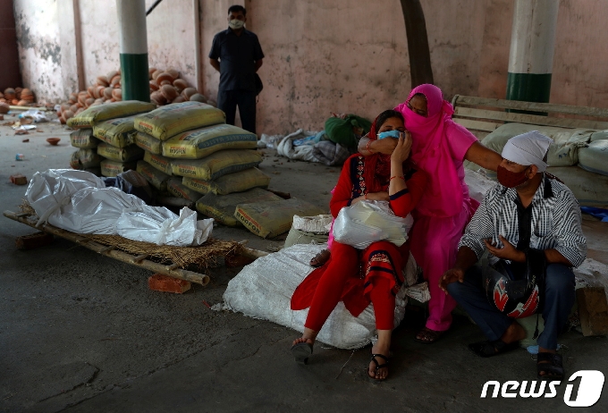 26일 인도 뉴델리에서 코로나로 숨진 희생자의 시신 옆에서 가족들이 오열하고 있다. © 로이터=뉴스1 © News1 박형기 기자
