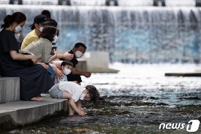 맑고 더운 날씨를 보인 20일 서울 청계천에서 아이들이 물장난을 치며 더위를 식히고 있다. 2021.6.20/뉴스1 © News1 유승관 기자