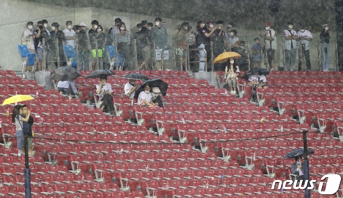 [사진] 갑자기 내리는 비에 경기장 아래 몸 숨긴 관중들