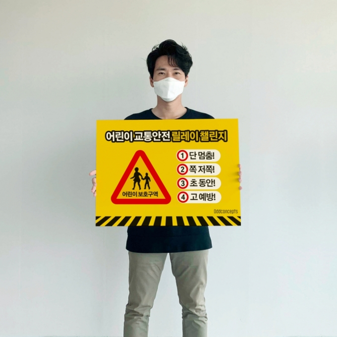 김정태 오드컨셉 대표가 어린이 교통 안전 릴레이 챌린지 캠페인 구호를 담은 팻말을 들고 있다/사진제공=오드컨셉
