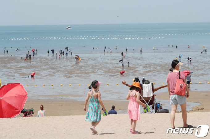 지난 25일 인천광역시 중구 을왕리해수욕장에 임시폐장을 알리는 플래카드 뒤로 피서객들이 물놀이를 즐기거나 모래사장에서 휴식을 취하고 있다 /사진=뉴스1 
