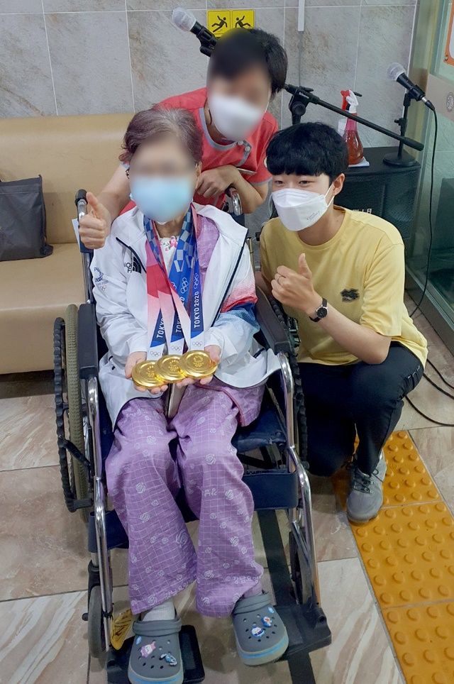 2020도쿄올림픽 양궁 '3관왕'을 거머쥔 안산 선수가 지난 2일 오후 광주 모 병원에 입원한 외할머니 목에 금메달을 걸은 뒤 함께 인증사진을 찍고있다./사진=뉴시스(독자제공)