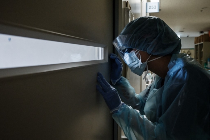 3일 일본 훗카이도대학병원에서 한 의료진이 문 너머로 코로나19 환자의 상태를 확인하고 있다./사진=AFP