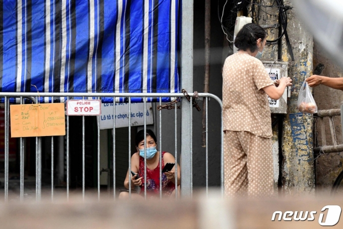 8월 24일 (현지시간) 코로나19 확산으로 봉쇄 조치가 내려진 베트남 하노이에서 주민이 바리케이드 뒤에서 음식을 기다리고 있다. /사진= AFP=뉴스1  
