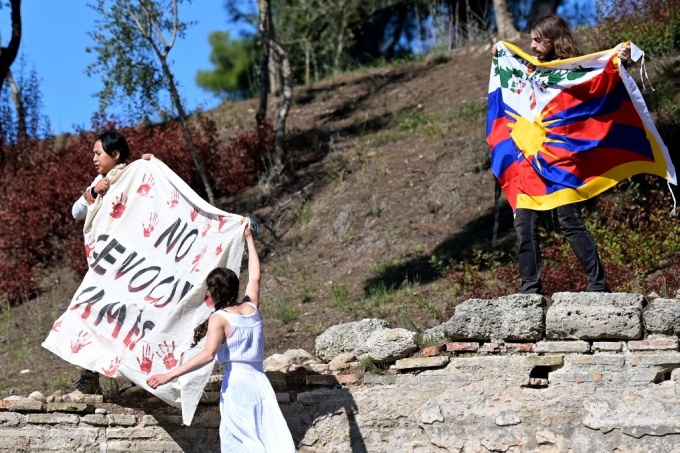 18일(현지 시간) 그리스 올림피아에서 베이징 동계올림픽 성화 채화식이 열리는 가운데 인권운동가들이 티베트 국기와 현수막을 펼치며 올림픽 개최 반대 시위를 벌이고 있다./사진=AFP 