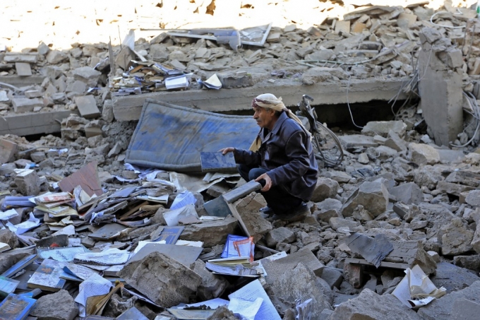 예멘 후티 반군의 공격에 대한 복수로 사우디 연합군이 예멘 수도 사나에 공습해 무너진 건물 더미에 예멘인이 앉아있다/사진=AFP